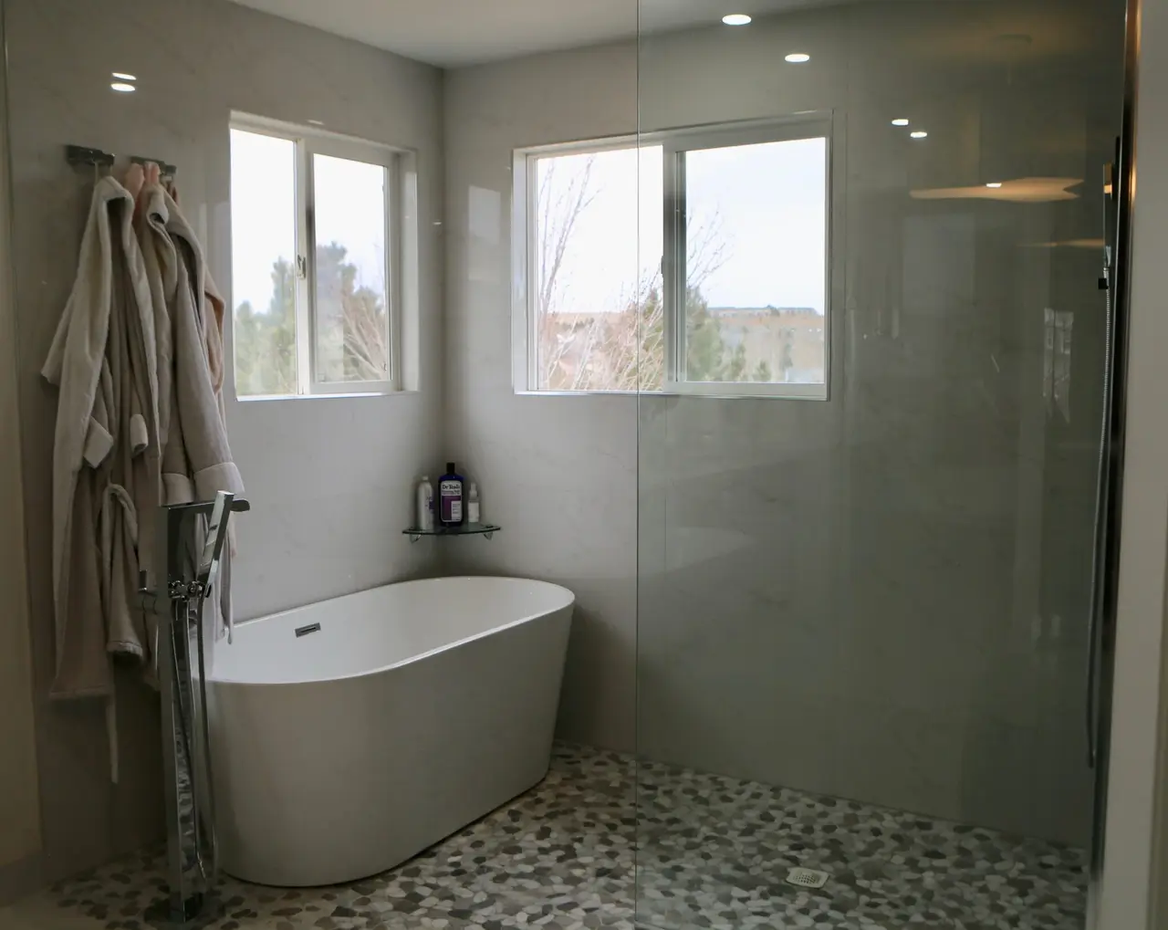 Remodeled primary bathroom in Broomfield, Colorado with a freestanding tub, a frameless glass shower and a pebble-tile floor