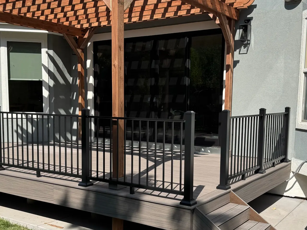 Back deck in Superior, Colorado with a wood pergola, black metal railings and steps down to the yard