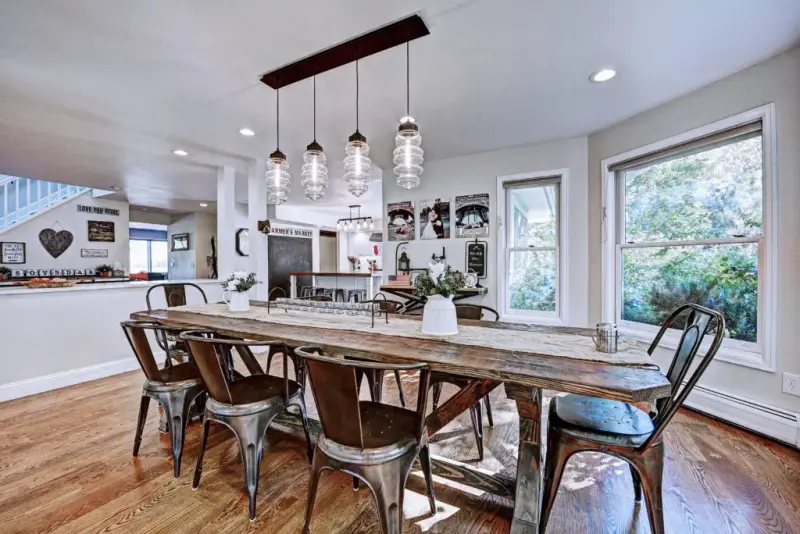 Open-concept kitchen and dining room in Boulder, Colorado with a long wood table, glass pendant lights and hardwood floors