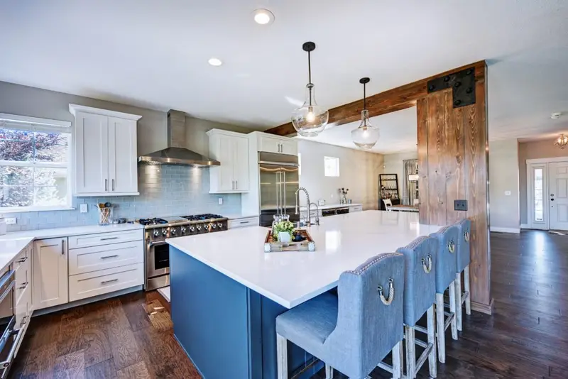 Main floor in Westminster, Colorado opened up around a navy kitchen island, with a wood-wrapped beam and post where a wall used to be